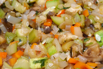 Vegetable stew is cooked on gas stove in metal pan. Vegetable ragout