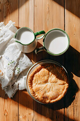 A warm and inviting scene featuring a traditional closed pie on a textured wooden table, a mug of milk and a soft white linen napkin, a cozy homemade breakfast mood,  calm morning, family gatherings