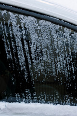 Obraz premium Frozen snow covers car window while streaks show where it has been scraped off on a cold winter morning