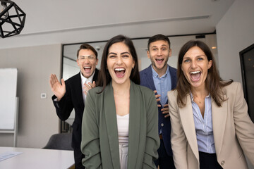 Obraz premium Four cheerful excited business colleagues laughing and shouting at camera