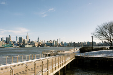 View of New York City skyline from waterfront pier on a sunny winter day with clear blue skies
