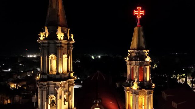 Drone flying upward from the illuminated church at night in the village of Chapala, Mexico