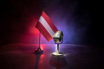 Microphone on a background of a blurry flag of Austria close-up. dark table decoration