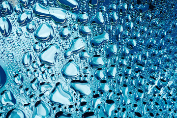 Water droplets on blue glass macro background