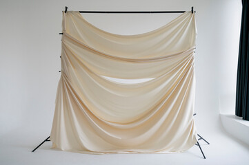 A beige silk backdrop on a stand in a photo studio