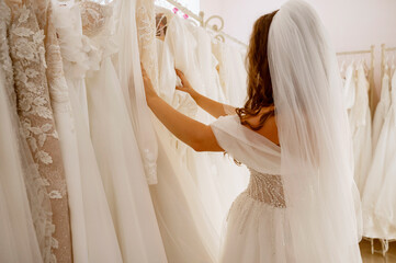 A young woman in a bridal salon chooses a wedding dress