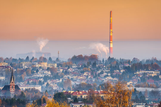 Industrial sunrise: smoke from power plant and waste incinerator chimneys over provincial polish city in autumn orange hues. CO2, pollution, ETS, European Union and its requirements