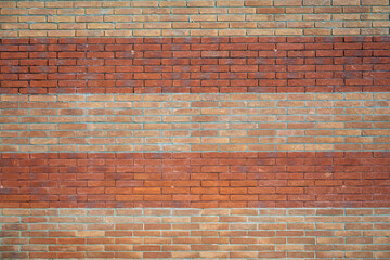 A brick wall with alternating red brick sections and beige