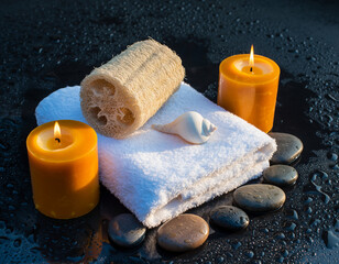 Spa still life with candles, towel, loofah, shell, and stones.