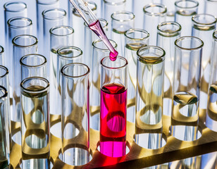 Chemical experiment: pink liquid being added to a test tube.