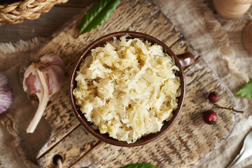 Fermented cabbage or sauerkraut in a brown clay pot on a table