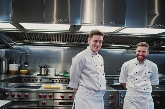 Professional chefs smiling in a modern kitchen during a culinary demonstration at a training facility