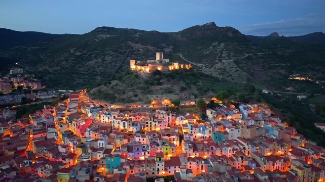 cinematic aerial shot capturing italian heritage site with illuminated streets and flowing river. Bosa. Italy