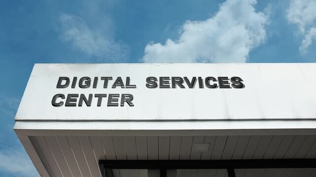 Digital Services Center word sign displayed on building facade with clear blue sky, showcasing a modern facility offering digital solutions and technology services