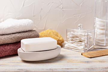 Health and hygiene. White soap bar elegantly positioned on dish, accompanied by neatly stacked towels and bathroom accessories, creating serene atmosphere for relaxation and self-care