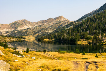 Panoramic view of Lake Aumar at sunrise, reflecting the mountains of the Néouvielle Nature Reserve