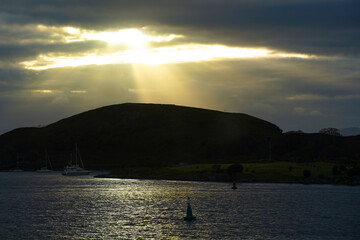 Sun-rays through the clouds at Oban bay in the Scottish highlands. In the back is the island Kerrera.