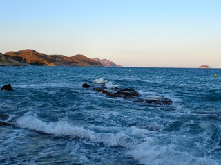 Obraz premium golden sunrise highlights rugged coastline with crashing waves and serene fishing vantage point