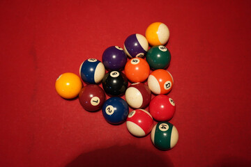 Close-up of billiard balls arranged on a red pool table under warm lighting