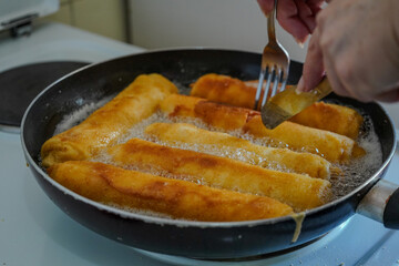 Close-up of piroshki(pirozhki) being fried in a pan filled with hot oil.