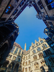 Upward view of the ornate courtyard towers and facades of Munich Rathaus framed by blue sky on a sunny day