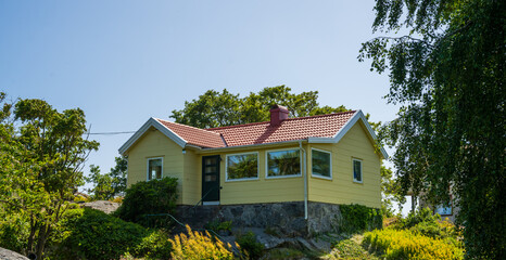 Small yellow cottage with red roof on hill.