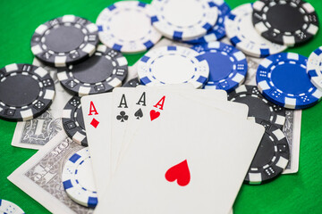 Four aces poker hand with chips and cash.