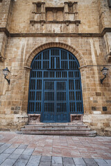 Large arched blue wooden door set in a weathered stone facade of a historic Oviedo building, with carved detail, wall lanterns and worn steps &mdash; dramatic architectural entrance