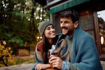 Happy couple drinking wine in backyard in autumn.