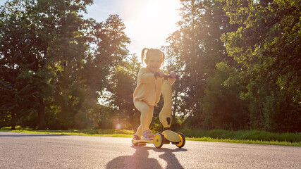 Girl on scooter. Riding child outdoor fun. Sunshine road freedom lifestyle.