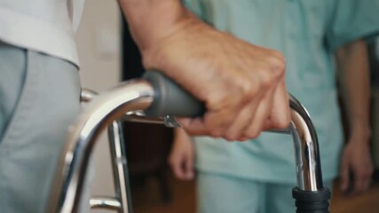 Elderly man using walker for support while walking during physical rehabilitation session. - Powered by Adobe