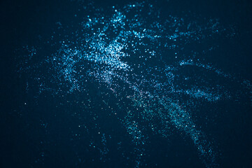 Macro view of shimmering blue glitter scattered on a dark surface, creating a sparkling abstract background with festive and elegant mood.