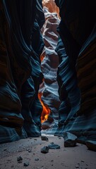 A narrow canyon with tall sculpted rock walls illuminated by an orange glow at its base Rocks scattered on the sandy floor