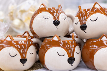 A collection of decorative ceramic plates and mugs with festive decorations. The plates depict winter landscapes, and the mugs are decorated with floral patterns.