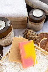 Two bars of handmade soap on a wooden tray. Slices of dried orange and pine cones are used as decorative elements.