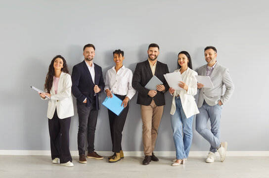 Happy business people team standing in row together with smiles, international professional group of corporate company staff. Confident and proud employees in office. Partnership, teamwork concept