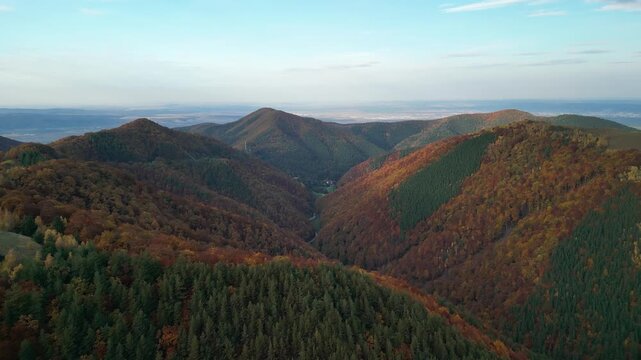 Breathtaking aerial view of a mountain range in autumn, showcasing vibrant foliage and serene valleys. Perfect for backgrounds, travel brochures, or nature-themed projects.