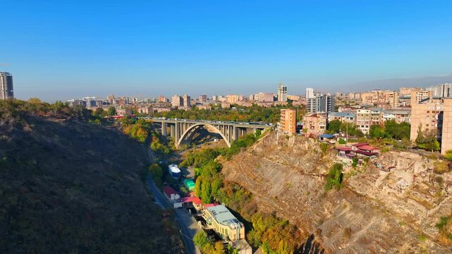 Yerevan Armenia city with a bridge Kievyan and a Hrazdan river running through it. The sky is blue and the buildings are tall