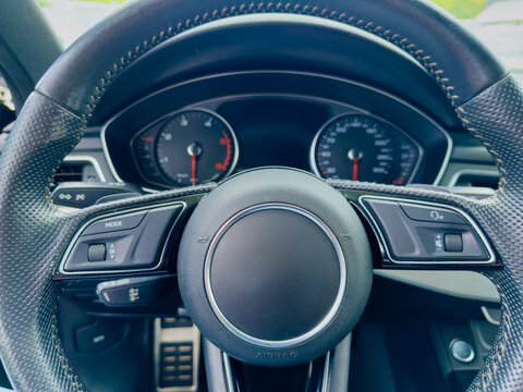 Exploring the interior of a modern vehicle with a focus on the steering wheel and dashboard features at a sunny afternoon