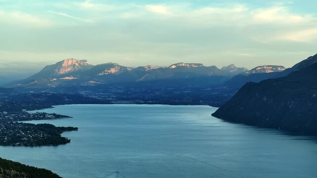 Aerial footage of a summer sunset above Lac du Bourget. The lake shines in evening light surrounded by mountains and forests.