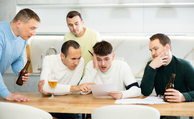 Brainstorming - male friends drinking beer and trying to solve financial problems by consulting each other while sitting at the table