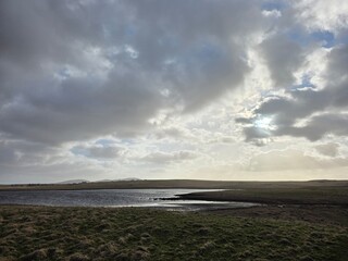 Overcast sky reflected in still loch across moorland, Isle of Lewis, Outer Hebrides, Scotland
