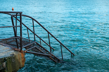 Rusty metal ladder into blue water.