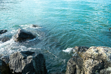 Blue ocean water splashing on coastal stones.