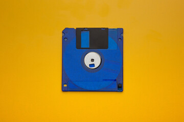 Vibrant blue 3.5-inch floppy disk centered on a bright yellow, contrasting back