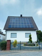 Modern residence showcases solar panels on its roof in a serene neighborhood with lush greenery and a well-maintained garden