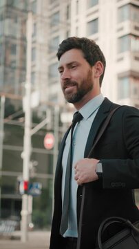 Smiling bearded man in business suit walks down city street