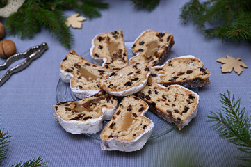 Winter pastries sliced ​​stollen with marzipan, raisins and candied fruits on a plate closeup