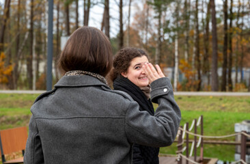 Friends Enjoying a Cheerful Moment Outdoors in a Park During Fall as One Waves Goodbye