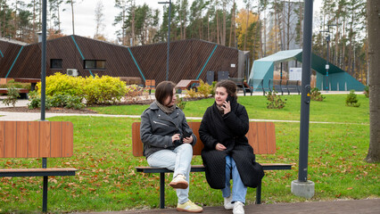 Two Friends Enjoying a Conversation on a Park Bench on a Cool Autumn Day in a Picturesque Urban Park